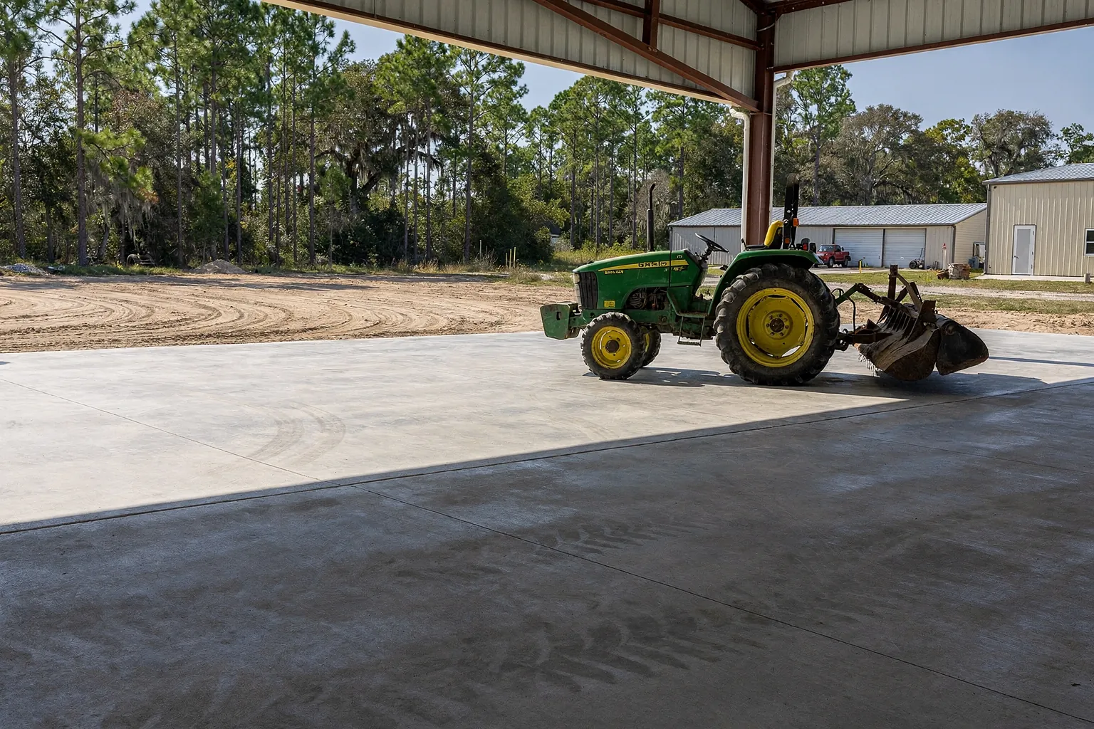 Thick reinforced pole barn floor with a tractor parked inside near Auburndale, Polk County